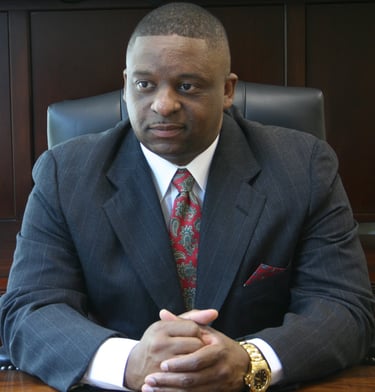 Mark T. Stewart in a suit and tie sitting at a desk