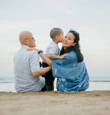 Parents and their son sharing a peaceful moment by the sea at Nusa Dua Beach Bali
