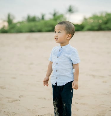 Young boy standing on the sand during a natural family photography session at Nusa Dua Beach Bali