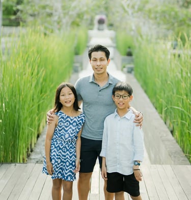 Family standing together on a tropical garden boardwalk during a luxury family photography session at The Ritz-Carlton Bali.