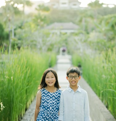Brother and sister standing on a garden boardwalk during a luxury family photography session at The Ritz-Carlton Bali.