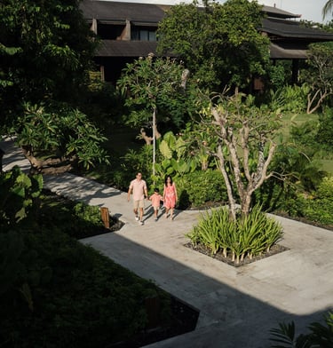 Family walking through tropical garden pathway at The Meru Sanur Bali during a relaxed family photography session