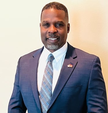 Dr. Marlon Ware standing in blue suit with blue striped tie