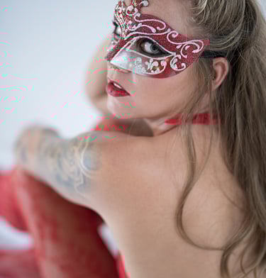 Boudoir-Portrait einer Frau mit kunstvoller rot-silberner Maske und roter Spitzenkleidung, aufgenommen im ästhetischen Finear