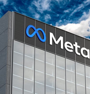 Low-angle view of the blue infinity symbol and Meta logo on a modern glass office building exterior.