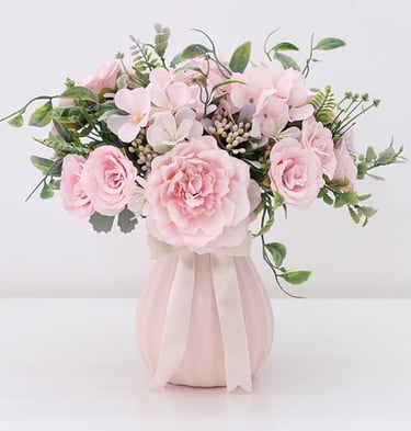 Elegant bouquet of pink silk peonies and roses in a fluted ceramic vase with a ribbon bow.