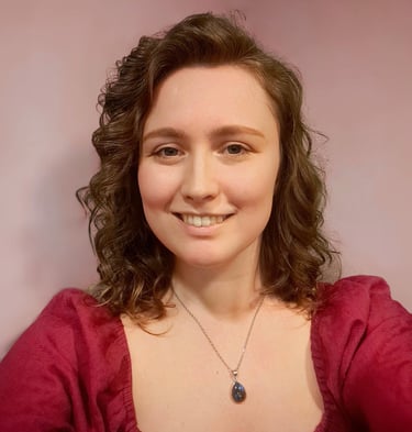 A photo of Katie Camm, the designer, smiling with a colorful backdrop