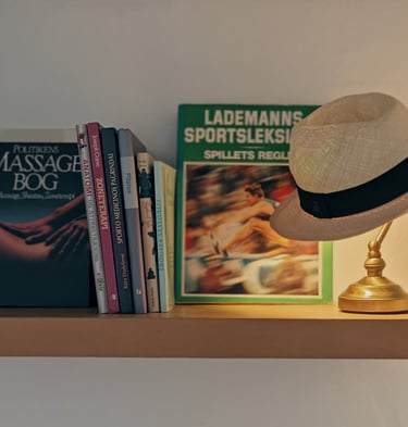 a hat on a shelf with books and a lemp