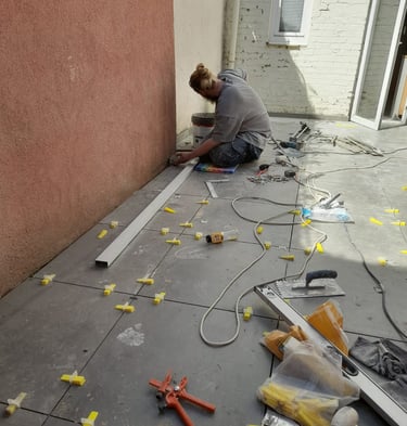 Pose de carrelage extérieur grand format en cours, avec croisillons de nivellement pour une finition