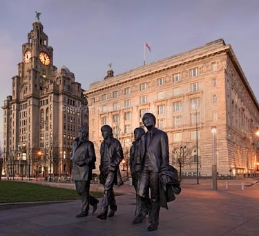 Beatles group of statues of four men walking down a street in Liverpool