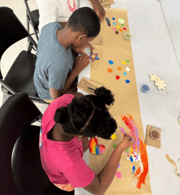 Two kids at arts and crafts table making crafts