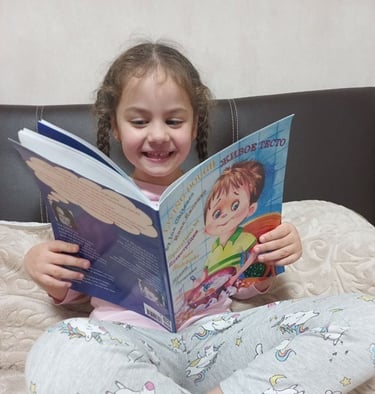 7-year-old girl reads Living Dough by Ina Chitenco on her bed, smiling and captivated by the story.