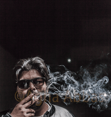 Gray-haired man in sunglasses, leather jacket, and beach t-shirt, holding cigarette with smoke, 