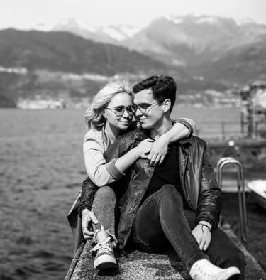 a man and woman sitting on a ledge overlooking the water