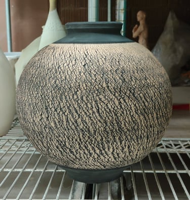 wheel-thrown moon jar with sodium silicate crack texture and black underglaze, awaiting high fire