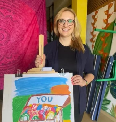 a woman holding a painting of a house