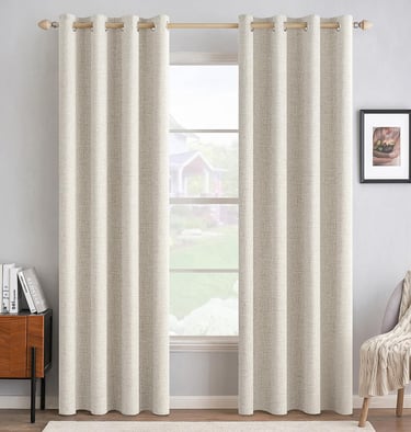 Beige textured linen blackout curtains with metal grommets hanging on a wooden rod over a window.