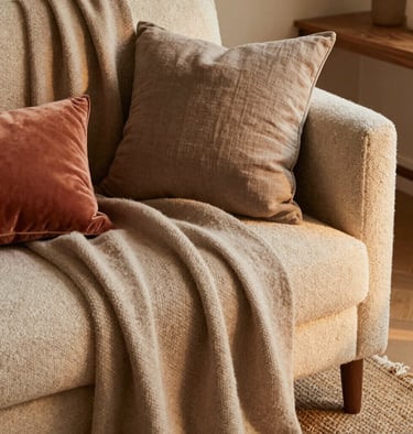 A cozy corner layered with earthy textiles and natural materials, evoking warmth and texture.