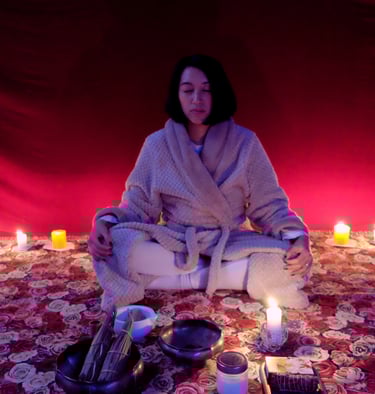 an asian woman on a meditative state with plenty candles on the back and ritual tools infront