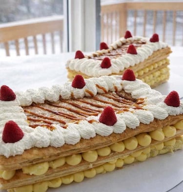 Pasteles de hojaldre con crema pastelera de vainilla, crema batida y frambuesas 