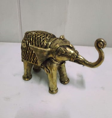 "Finely crafted brass baby elephant with raised trunk and ornate tribal motifs-For global distribution"