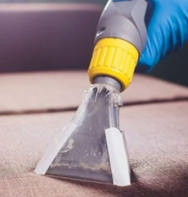 Nettoyage professionnel d'un canapé par NetT : utilisation d'un aspirateur à embout transparent par un expert en gants bleus