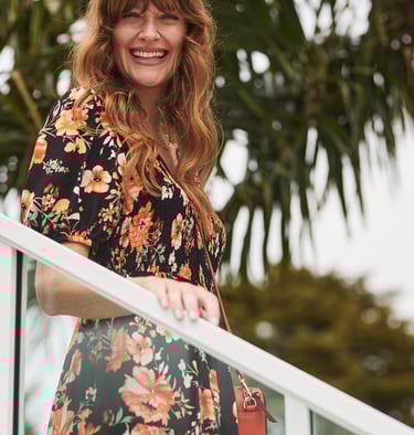 Fashion campaign photography - a woman in a floral dress and a red purse walking down stairs