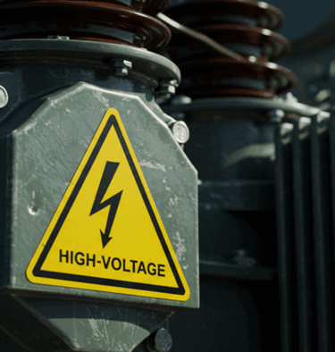Yellow high-voltage warning sign with a lightning bolt on industrial electrical equipment.