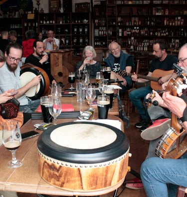 Musicians playing traditional folk music with guitars, banjo, and bodhrán drum in an Irish pub.