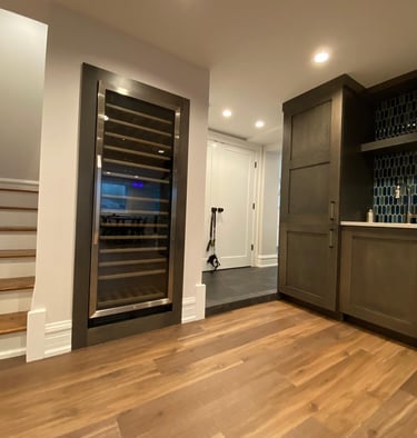 Professional basement finishing with modern flooring, and build in wine cooler refrigerator