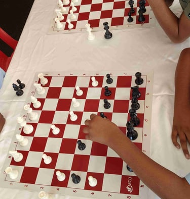 Two students in school uniforms playing a competitive game of chess on a red and white board.