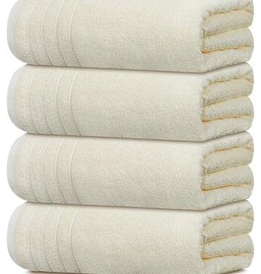 Stack of four plush cream organic cotton bath towels.
