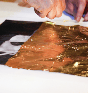 a person who applies 24-carat gold leaf on a photographic print