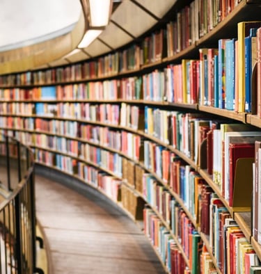a library with a long row of bookshelves and a circular glass window