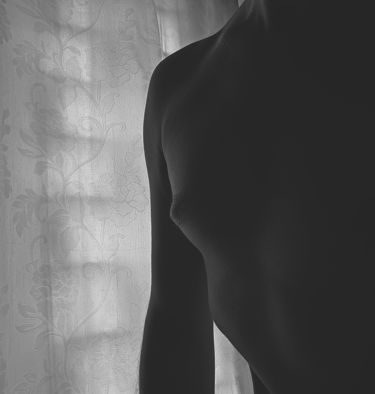 Hombre artístico de cuerpo humano en blanco y negro frente a una cortina floral.