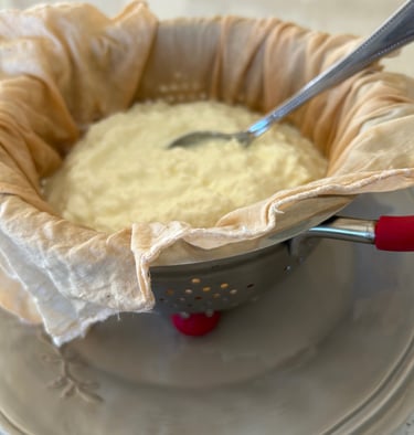 yoghurt being strained through a cheese cloth in a metal colander