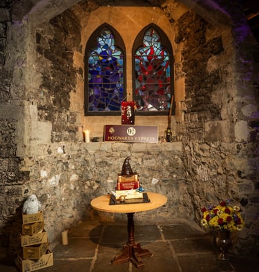 Harry Potter–themed birthday cake table by stone wall and stained glass, Fred Art Studio.