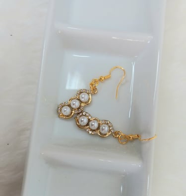 a pair of earrings with pearls and gold