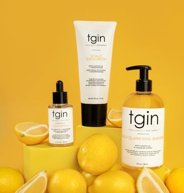 TGIN scalp care products with lemon oil and niacinamide displayed with fresh lemons on a yellow background.