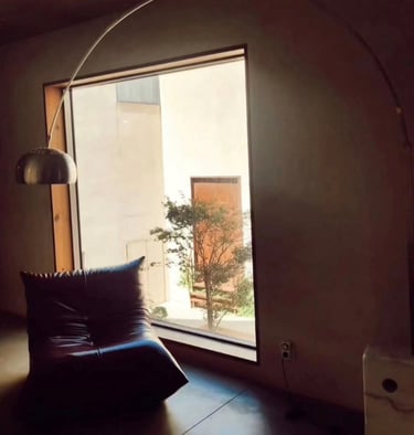 Modern living room featuring a leather Togo chair, large window with a view, and an arched floor lamp.