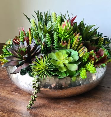 a silver bowl with artificial succulent plants in it