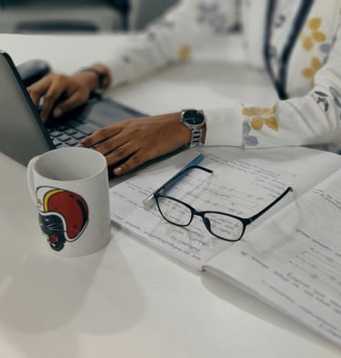a woman sitting at a desk with a laptop and a cup of coffee
