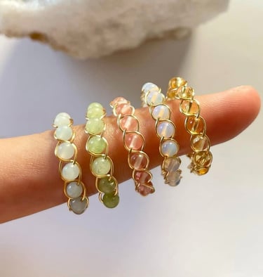 Anillos de alambre dorados con cuentas de diferentes colores en un dedo.