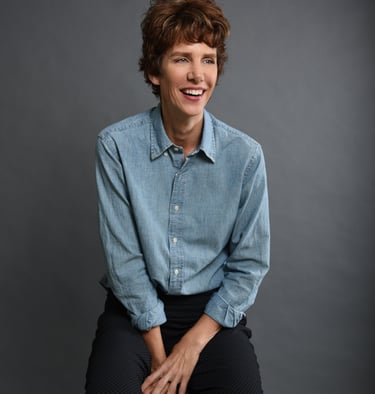 professional studio photo of author Dawn Davies sitting on a bench and smiling