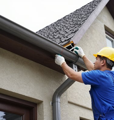 Close-up of clean gutters with water flowing smoothly, surrounded by green leaves.