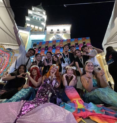 a group of mermaids posing infront of a night light city backdrop