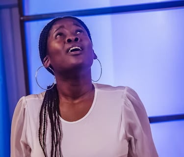 A woman looks upward in worship, expressing faith, hope, and a search for truth.