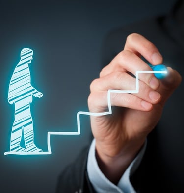 Person drawing a glowing silhouette of a figure climbing stairs, symbolizing progress and growth.