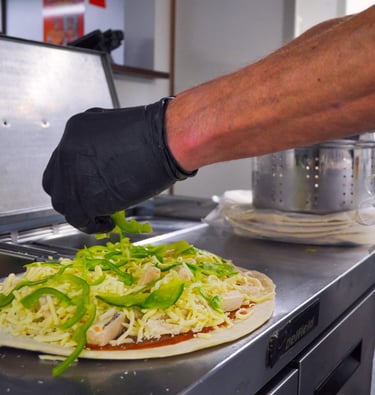 a person wearing gloves and gloves is preparing to make a pizza