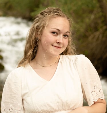 a woman in a white dress standing in front of a river
